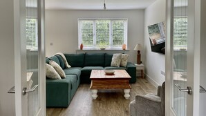 A modern living room with a sectional sofa, a wooden coffee table, and a television on the wall.