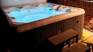 A hot tub with a wooden bench and a window with blinds.