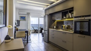 Eine moderne Küche mit großem Kühlschrank, Backofen und integrierter Mikrowelle. Ein Essbereich mit Tisch und Stühlen lädt zum Verweilen ein, und große Fenster bieten Blick auf den Ozean.