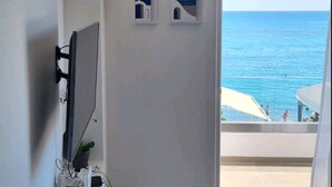 Ein modernes Zimmer mit Flachbildfernseher, einem Glastisch und Meerblick.