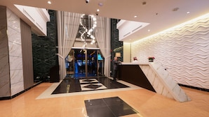 Een hotellobby met een receptiebalie, een incheckbalie en een geometrisch vloerpatroon.