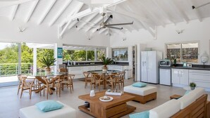 A spacious living area with a high ceiling, wooden furniture, and a view of the outdoors.