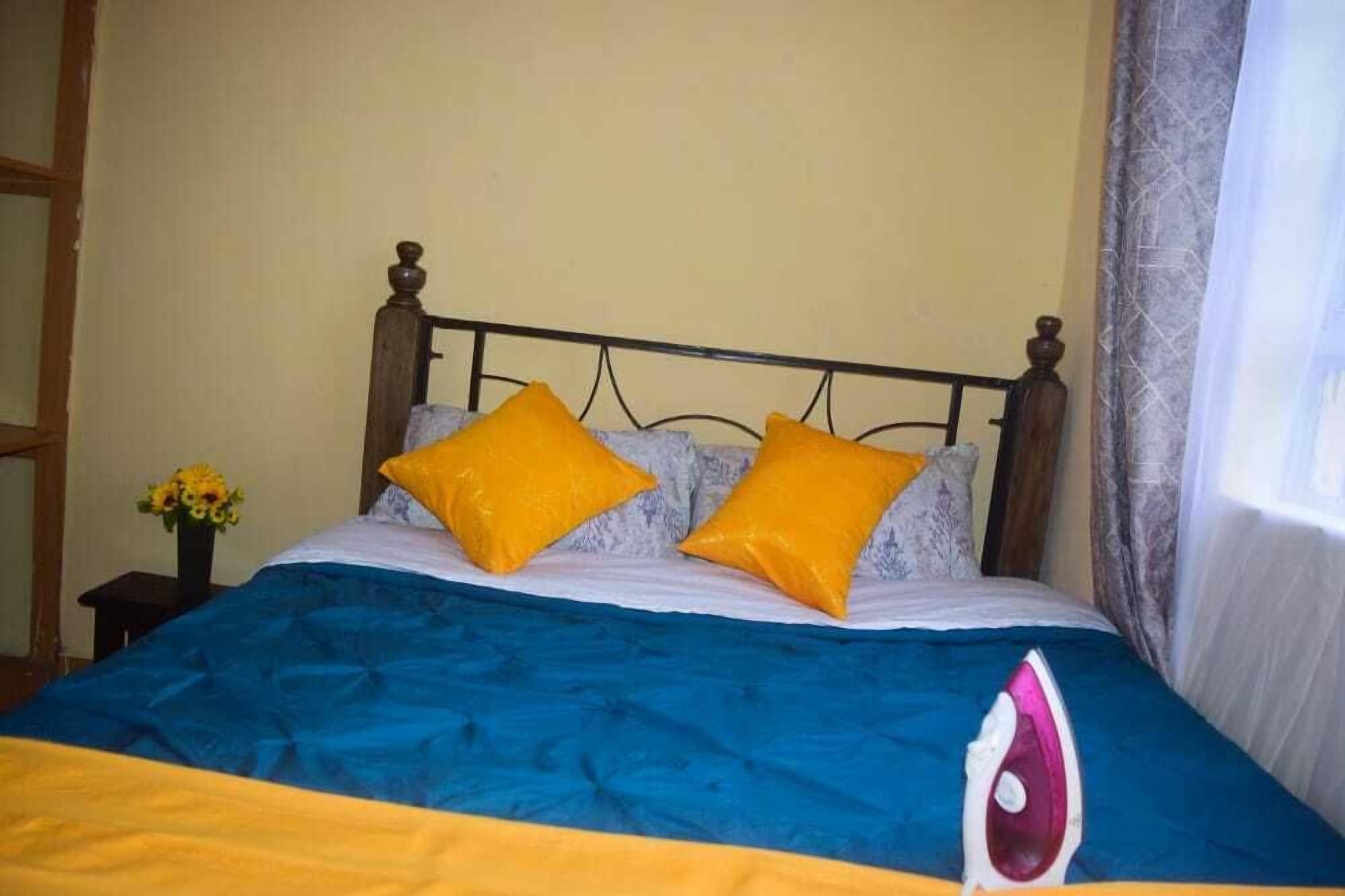 Een bed met een blauw-geel dekbed, twee gele kussens en een houten hoofdbord.