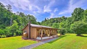 Een houten chalet met een veranda, omgeven door een verzorgd gazon en dicht bos.