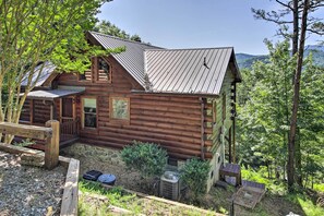 Una rustica baita di tronchi con fondamenta in pietra, una veranda in legno e vista sulla foresta circostante.