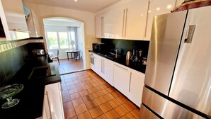 Una cocina moderna con armarios blancos, un refrigerador de acero inoxidable y una encimera negra.