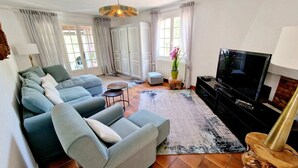Una sala de estar con un sofá modular, un televisor de pantalla plana, una mesa de centro y una planta en maceta.