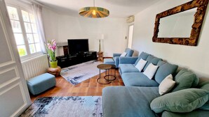 Una sala de estar con un sofá, un televisor, una lámpara y un espejo decorativo.