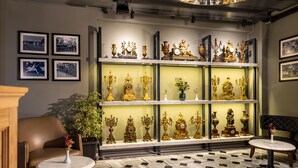 Una habitación con piso estampado, un sofá, una mesa con un florero y una exhibición de relojes dorados.