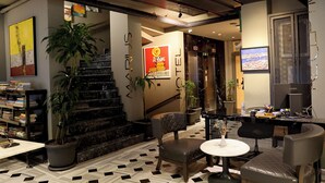 Un vestíbulo de hotel con una escalera, una zona de estar y una recepción.