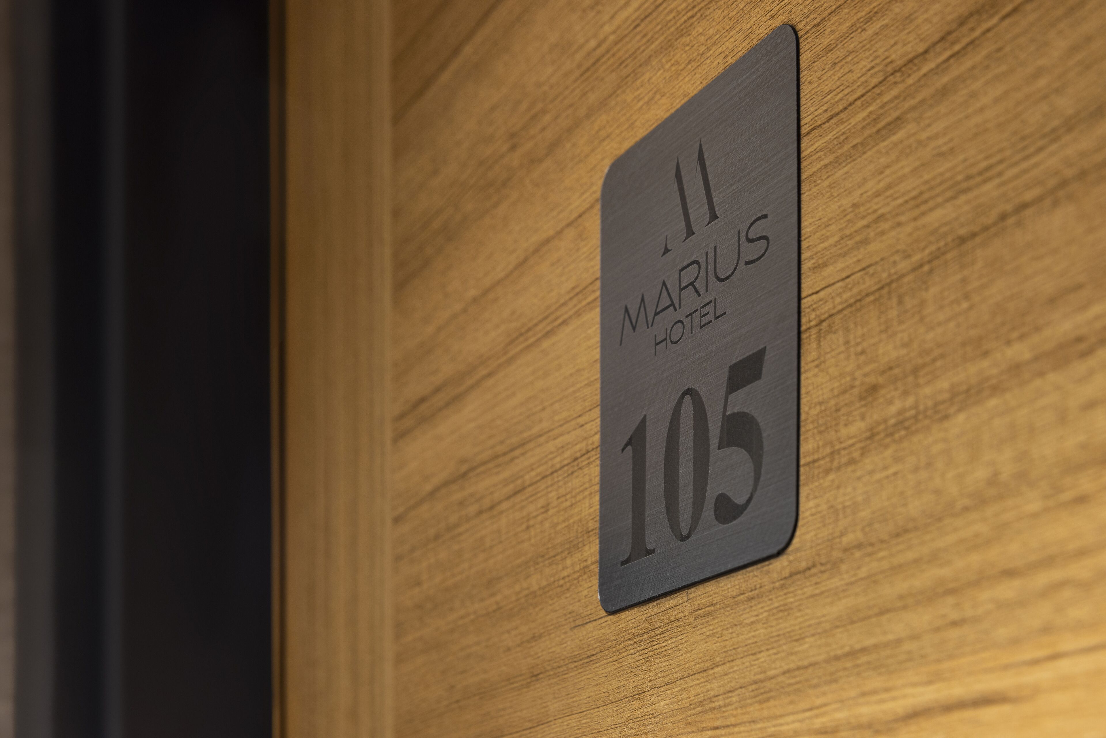 A hotel room number sign with the text "MARIUS HOTEL 105" on a wooden wall.