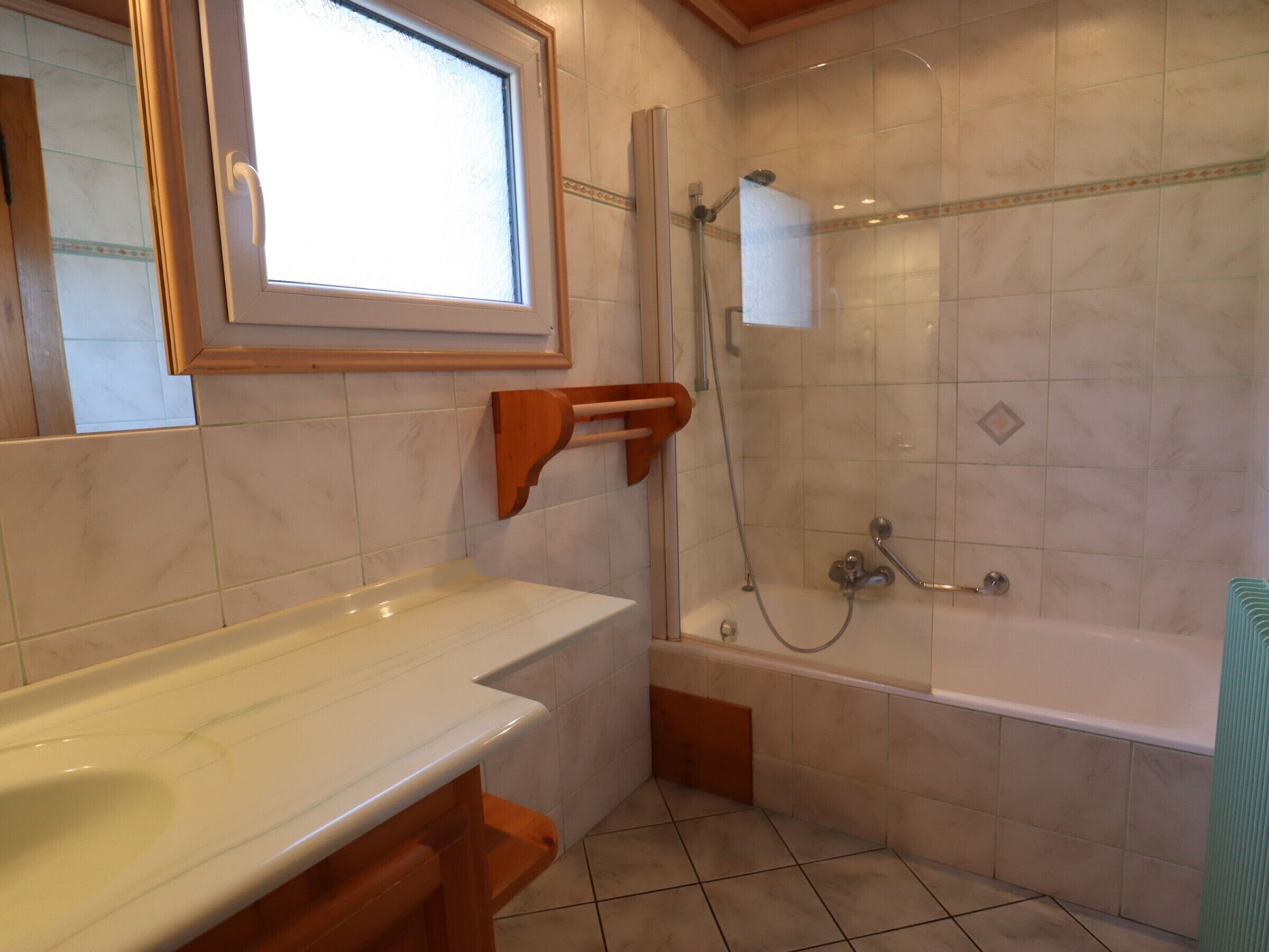 A bathroom with a bathtub, a shower, and a window.