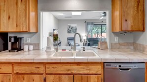 Una cocina moderna con armarios de madera, lavavajillas integrado y un lavamanos grande.