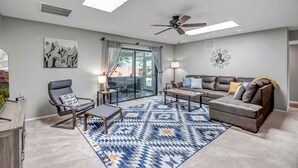 Una sala de estar moderna con sofá, sillón, mesa de centro y alfombra estampada.