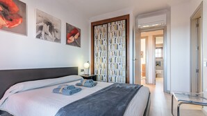 Habitació d'hotel amb un llit gran, una estanteria i obres d'art a la paret.