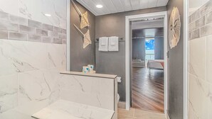 Ein modernes Badezimmer mit Marmorfliesen, einer Duschkabine und Blick auf einen Balkon.