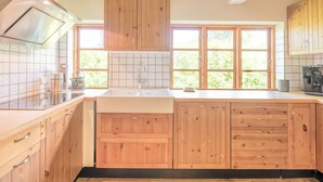 Una cucina con mobili in legno, una cappa aspirante in acciaio inossidabile, un lavello a due vasche e una finestra che lascia entrare luce naturale.