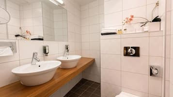 A modern bathroom with two sinks, a mirror, and a toilet.