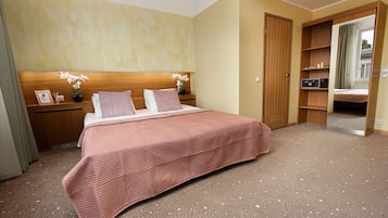 A hotel room with a large bed, wooden headboard, and a mirror cabinet.