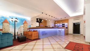 Vestíbulo de hotel con mostrador de recepción, zona de estar y un gran mural de un castillo.