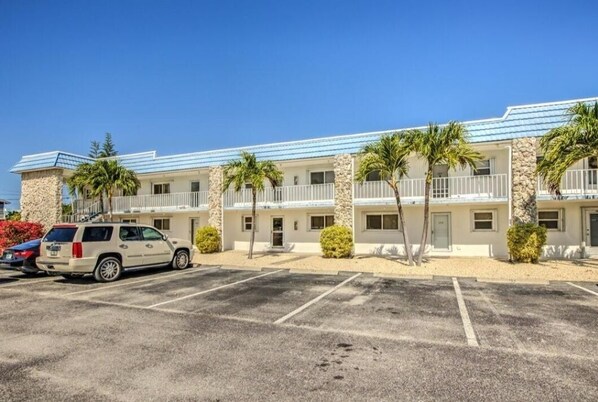 Ein Motel mit einer Reihe von Zimmern, jedes mit einem Balkon und einer Steinfassade. Vor dem Gebäude befindet sich ein Parkplatz.