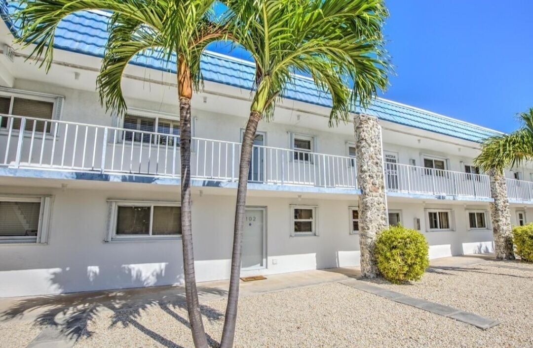 A two-story motel with a white exterior, blue roof, and a balcony on the second floor.