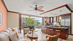 Cocina moderna con una isla central, taburetes de bar y vistas a un área residencial.