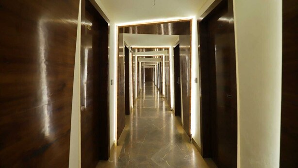 A long, narrow hallway with dark wooden doors and a polished marble floor. - Hotel Skylark (Bareilly)