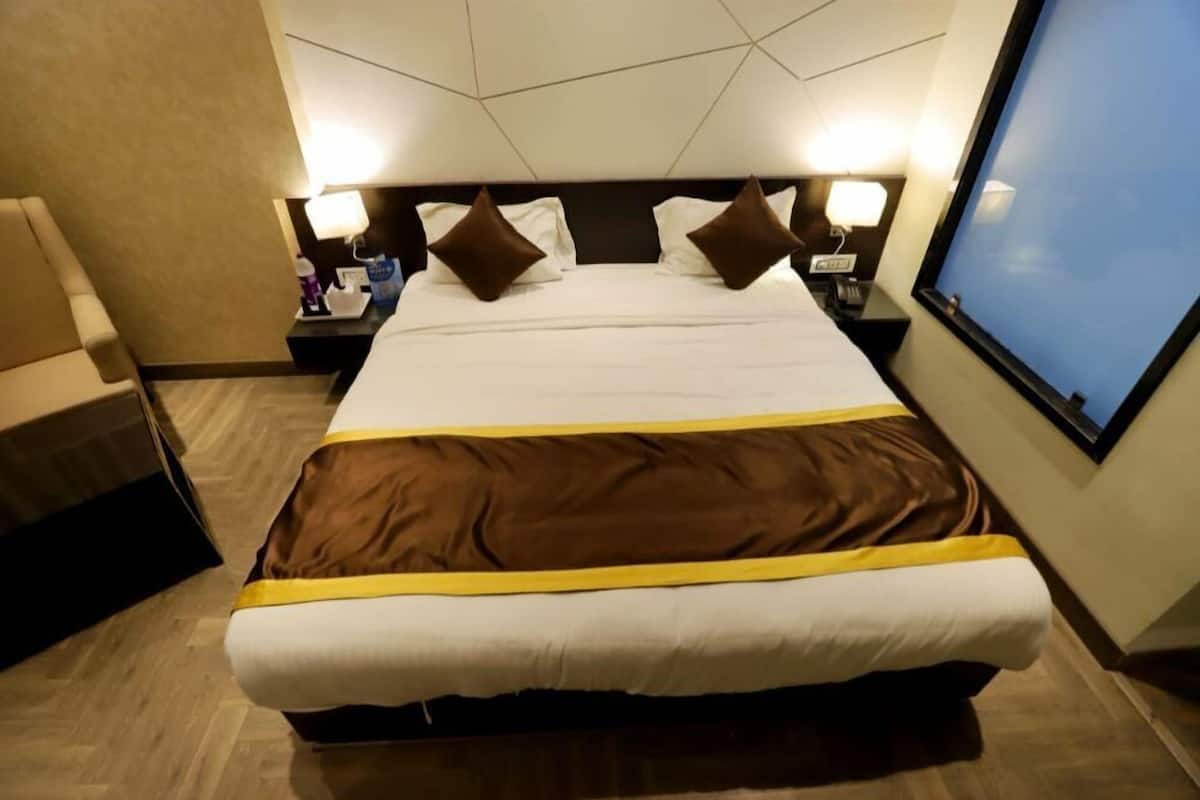 A hotel room with a large bed, two bedside tables, a chair, and a large window.