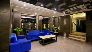 A lobby with blue sofas, a coffee table, and potted plants. - Hotel Skylark (Bareilly)