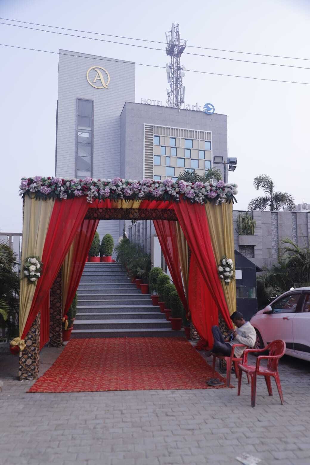 A hotel entrance with a red and gold archway, steps leading up to the entrance, and a red carpet.