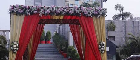 A hotel entrance with a red and gold archway, steps leading up to the entrance, and a red carpet.
