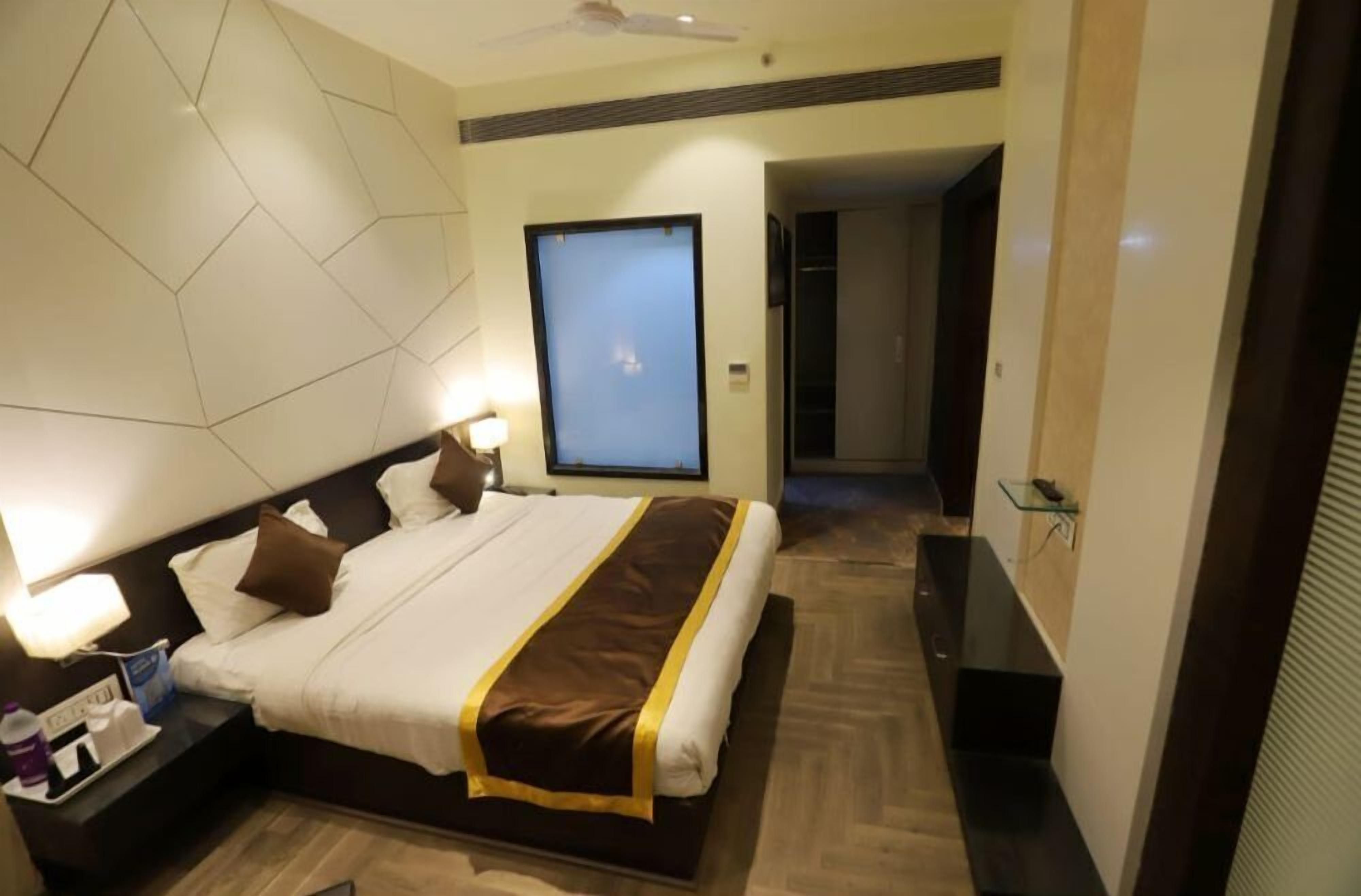 A hotel room with a large bed, bedside lamps, a flat-screen TV, and a modern design.