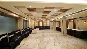 A spacious conference room with a marble floor, rows of black chairs, and a long table in the center. - Hotel Skylark (Bareilly)