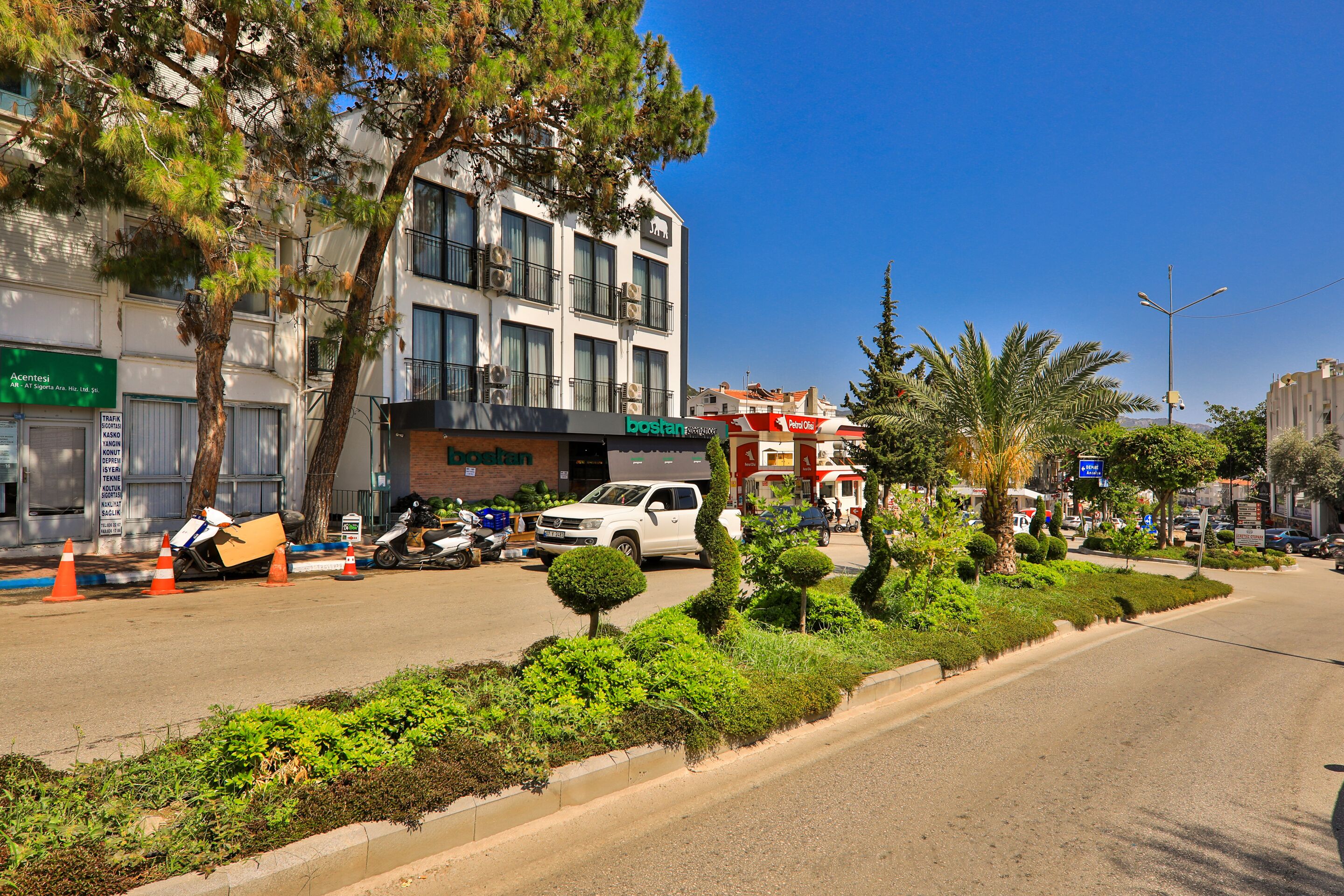 A street with a building that has a sign for 'COSTA' and a parked white SUV.