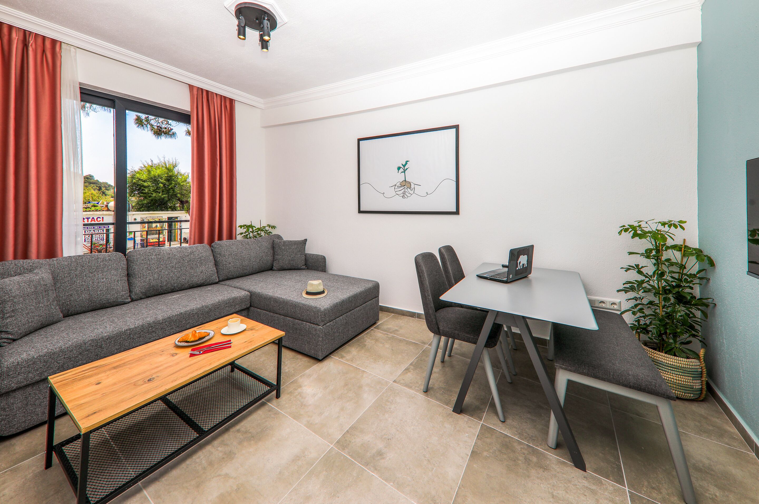 Una sala moderna con un sofá seccional gris, una mesa de centro de madera, una mesa de comedor con sillas y una obra de arte enmarcada en la pared.