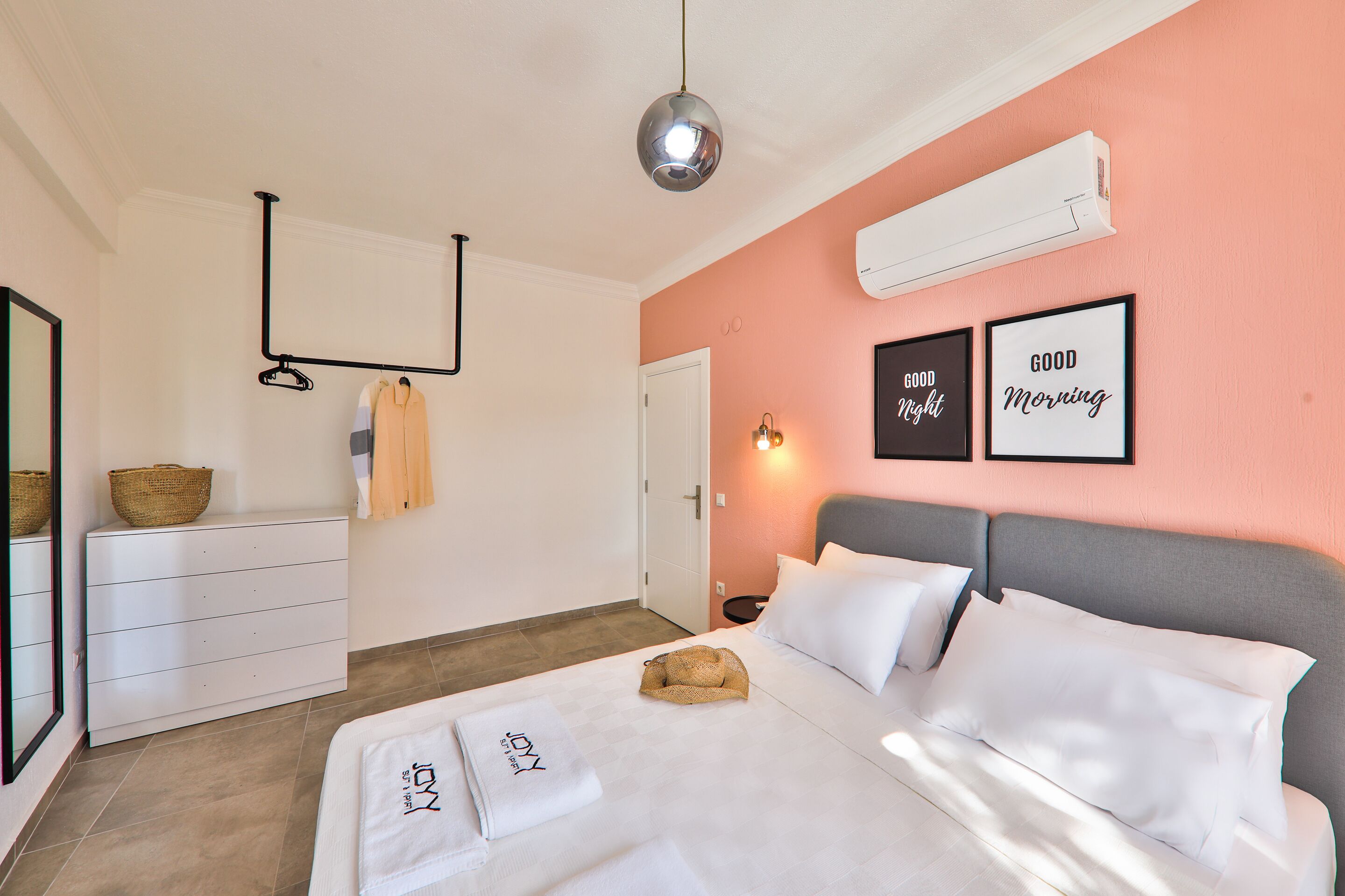 A bedroom with a bed, a dresser, a mirror, and a wall-mounted air conditioner.