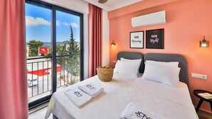 Una habitación de hotel con cama, ventana con vistas a la ciudad, balcón y aire acondicionado instalado en la pared.