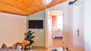 Una sala de estar con un sofá, una mesita con una planta y un televisor de pantalla plana montado en la pared.