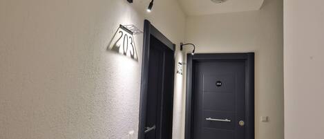 A hallway with two doors, one labeled 203 and the other 204, and a wall-mounted light fixture.
