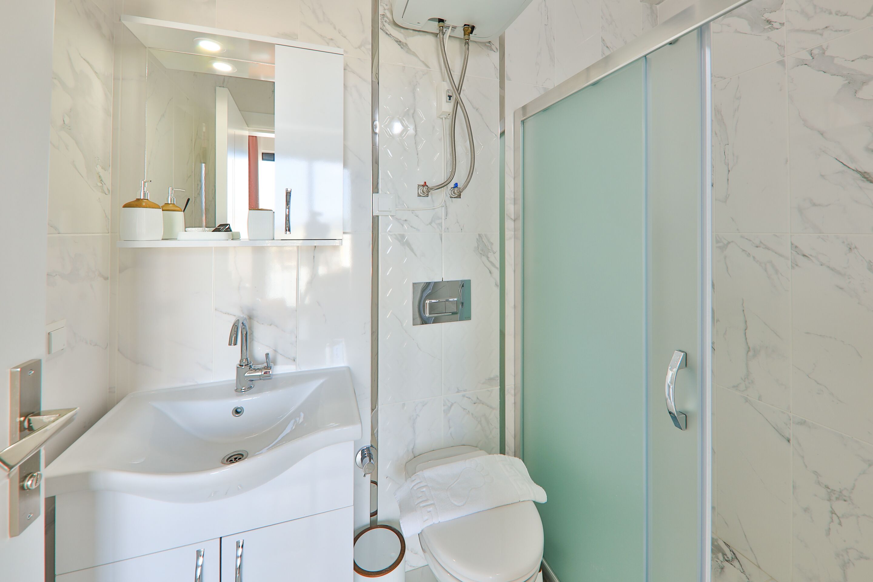 Een badkamer met een wit wastafelmeubel, een toilet en een douchegedeelte.
