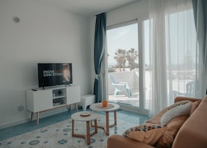 A modern living room with a TV, a sofa, a small table, and a balcony with a chair. - Holiday Home "Misalmar Superior" with Sea View, Terraces & Wi-Fi (San Lorenzo)