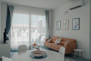 A modern living room with a sofa, a dining table, and a TV. - Holiday Home "Misalmar Superior" with Sea View, Terraces & Wi-Fi (San Lorenzo)