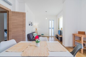 A modern living room with a dining table, sofa, and a small side table with a basket.