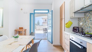 A modern kitchen with a dining area, a view to the outside, and a small table with a plant.