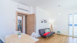 A modern living room with a dining table, sofa, and a small side table.