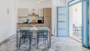 A modern kitchen with a dining table and chairs, a microwave, and a blue-framed door leading to another room. - Holiday Home "MisMar 2" with Sea View, Garden & Wi-Fi (Noto)