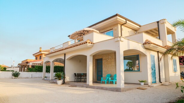 A two-story building with a covered patio, outdoor seating, and a view of the surrounding area. - Holiday Home "MisMar 2" with Sea View, Garden & Wi-Fi (Noto)