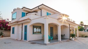 A two-story house with a balcony, a covered porch, and a gravel driveway. - Holiday Home "MisMar 2" with Sea View, Garden & Wi-Fi (Noto)