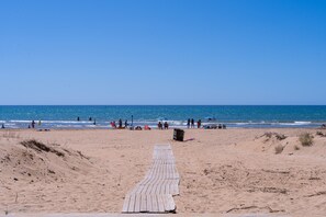 A beach with a wooden walkway leading to the water, people in the distance, and a clear sky. - Pet-Friendly Holiday Home 'Casa Dorotea' with Sea View & Terraces (Tre Fontane)